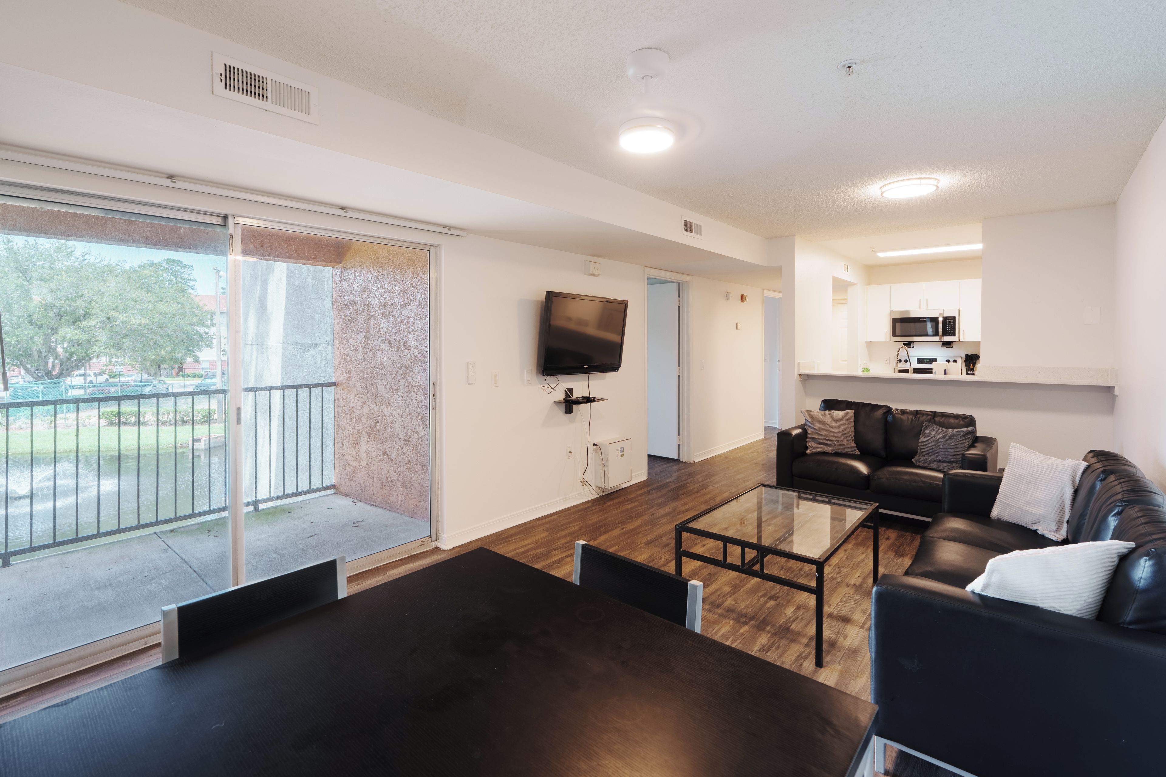 A modern living room with a flat-screen TV, a dining table, and a sofa.