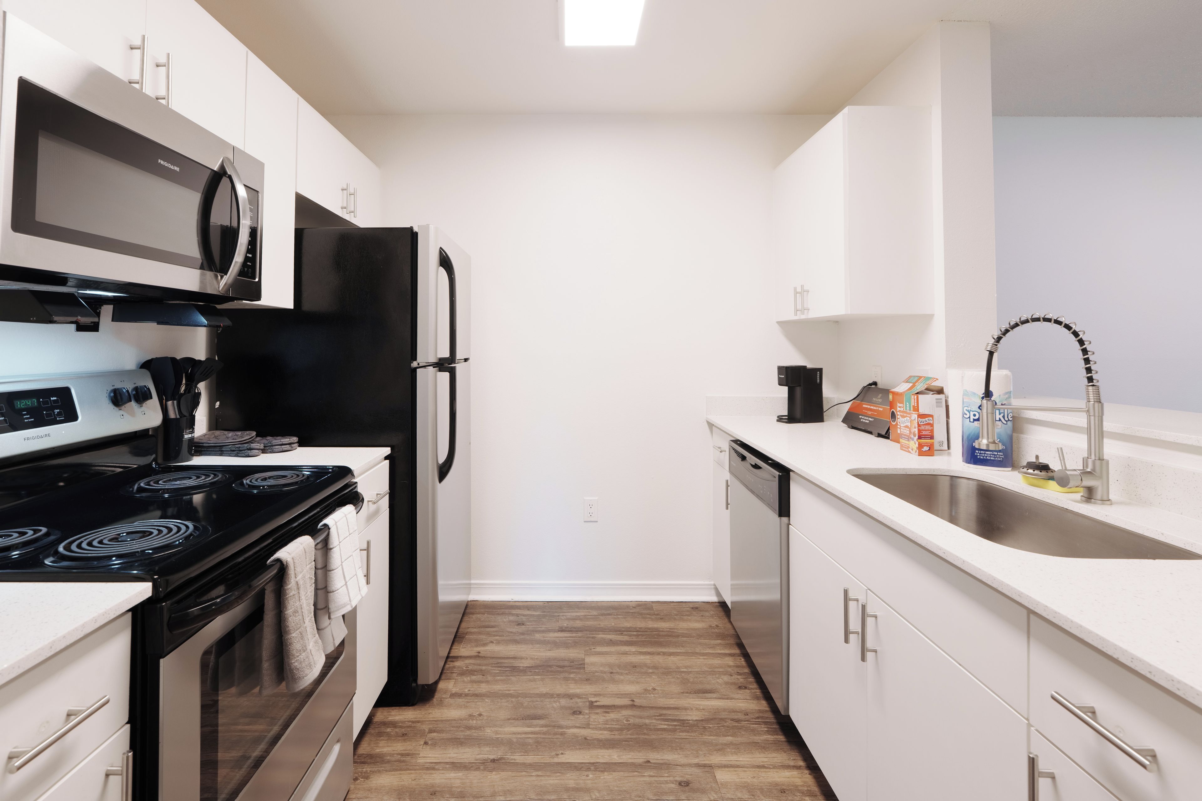 Una cocina moderna con armarios blancos, un refrigerador negro, un microondas, una estufa y un lavavajillas.
