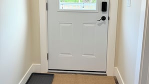 A white door with a window, a doormat, and a small step leading to the door.