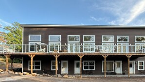 A two-story building with a balcony, multiple windows, and a covered porch area.