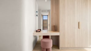 A modern interior with a wooden wardrobe, a small stool, and a minimalist desk area. - Sol Coastal Luxury in Bondi Beach (Bondi Beach)