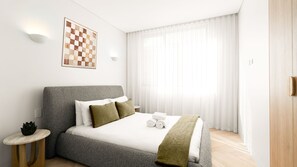 Ein modernes Hotelzimmer mit einem großen Bett, einem kleinen Nachttisch, einer Wandleuchte und einem Fenster mit durchsichtigen Vorhängen.