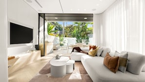 A modern living room with a sofa, coffee table, and TV. - Sol Coastal Luxury in Bondi Beach (Bondi Beach)