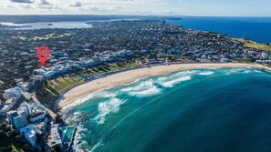 Vista aérea de una ciudad costera con playa, edificios residenciales y un punto de referencia destacado.