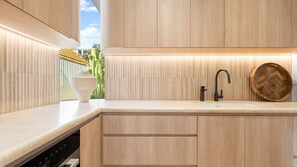 Eine moderne Küche mit eingebautem Geschirrspüler, einer Holz-Rippen-Spritzschutzleiste und einer runden Holtschüssel auf der Arbeitsplatte.