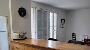 Una cocina con un armario de madera, un reloj y un ventanal.