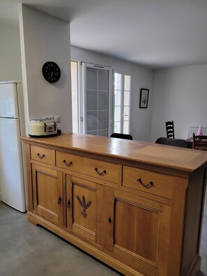 Een keuken met een houten kast, een klok en een raam.