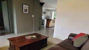 Una sala de estar con un sofá de cuero marrón, una mesa de centro de madera y un cojín a rayas.