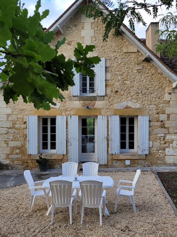 A stone building with a traditional design, featuring a balcony and a table with chairs outside.