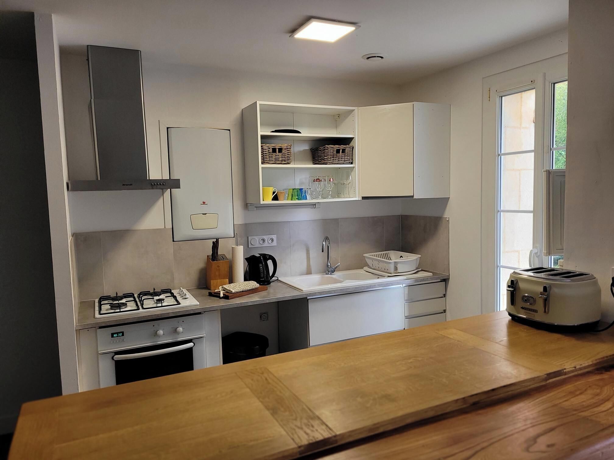 A modern kitchen with white cabinets, a gas stove, a built-in oven, a coffee maker, and a toaster.