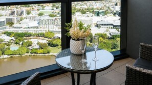 Ein Balkon mit Tisch, zwei Stühlen, einer Blumenvase und einem Glas Wasser.