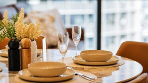A dining table with a vase of flowers, two wine glasses, and a bowl set. - The Elysian on Margaret at Queen's Wharf (Brisbane City)