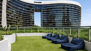 A modern building with a curved facade and a rooftop garden with seating. - The Elysian on Margaret at Queen's Wharf (Brisbane City)
