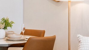 Et spiseområde med et bord dækket til to personer, en vase med blomster og en stor gulvlampe.