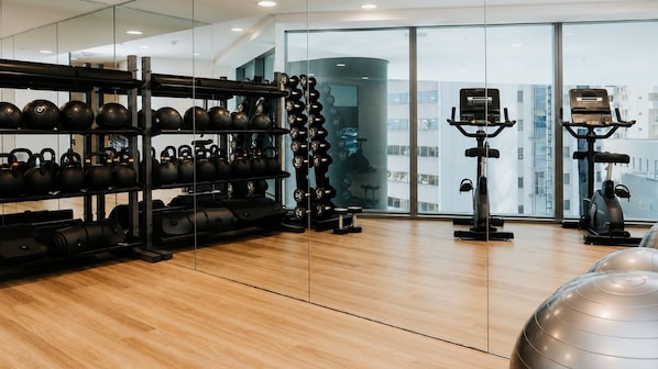 Et fitnessrum med kettlebells, håndvægte og træningsudstyr.