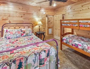Une pièce avec un intérieur en bois, un cadre de lit en métal, une table de chevet avec une lampe et un lit superposé avec une literie à motifs.