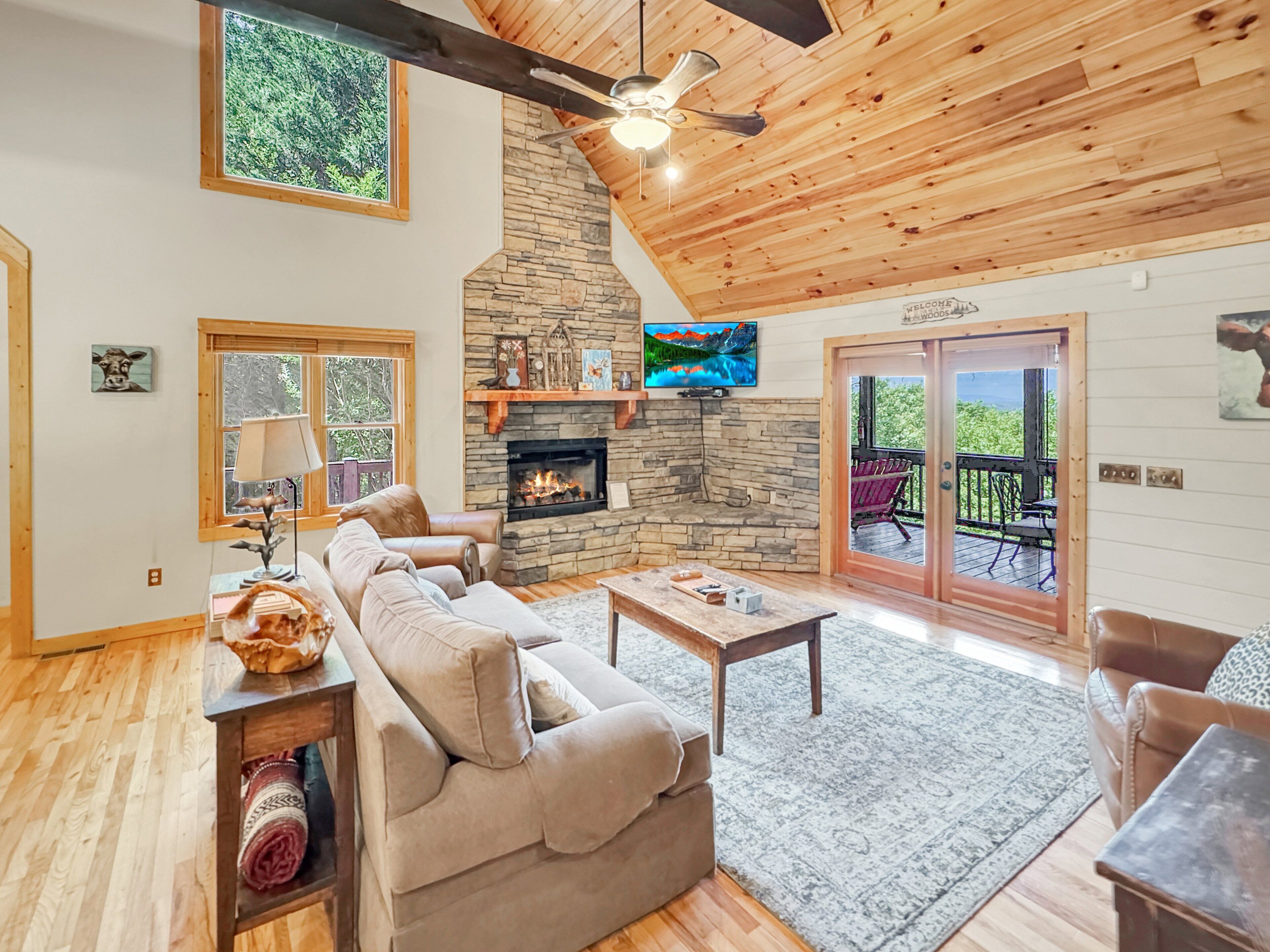 A cozy living room with a stone fireplace, leather sofa, and a television mounted on the wall.
