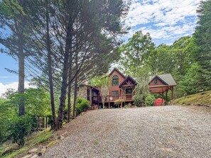 A lodge with a stone facade, wooden deck, and a gravel driveway. - Mountain Melody - Mountain View | Pet Friendly | Hot Tub | Game Room (Morganton)