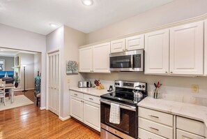 A modern kitchen with white cabinetry, a stainless steel microwave, and a gas stove. - Tall Ship 337 Keowee Key (Salem)