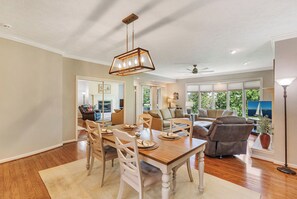 A spacious dining area with a wooden table and chairs, a chandelier, and a view of the outdoors through large windows. - Tall Ship 337 Keowee Key (Salem)