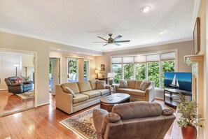 A spacious living room with a large sofa set, a coffee table, and a television. There is a ceiling fan, a fireplace, and large windows offering a view of the outdoors. - Tall Ship 337 Keowee Key (Salem)