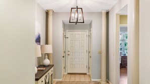 Um corredor com uma porta branca, uma luminária e um tapete.
