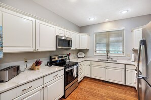 A kitchen with white cabinets, a stainless steel microwave, a stove, and a sink. - Tall Ship 337 Keowee Key (Salem)