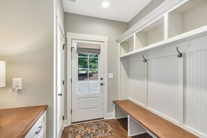 A hallway with a white door, a bench, a wall-mounted shelf, and a doormat. - McAlister Rd Simply Spectacular (West Union)