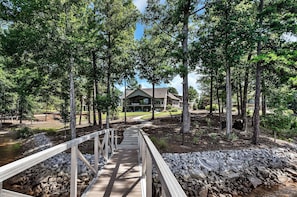 A wooden bridge leading to a building surrounded by trees. - McAlister Rd Simply Spectacular (West Union)