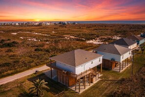 Ein Wohngebiet mit Häusern im Bungalowstil, Holzbalkonen und Blick auf den Ozean bei Sonnenuntergang.