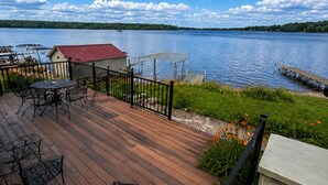 Um deck de madeira com móveis de exterior, com vista para um lago.