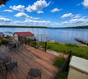 Eine Holzterrasse mit Gartenmöbeln mit Blick auf einen See.