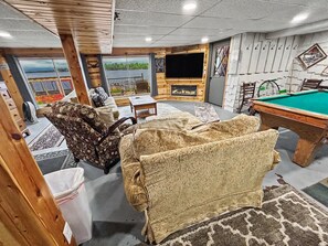 Un espace intérieur accueillant avec une table de billard, des sièges confortables et une cheminée.