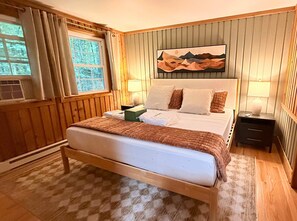 Ein Schlafzimmer mit einem hölzernen Bett, einem Nachttisch, einer Lampe und einem Bild an der Wand.