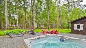 A hot tub surrounded by a deck, red chairs, and a hammock in a forested area. - Firelight Escape w/ Hot Tub, Games & Resort Access (Tobyhanna Township)