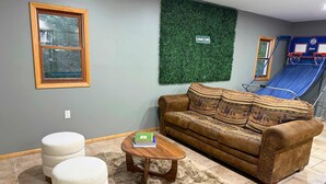 A living room with a brown leather sofa, a wooden coffee table, and a shaggy rug. - Firelight Escape w/ Hot Tub, Games & Resort Access (Tobyhanna Township)