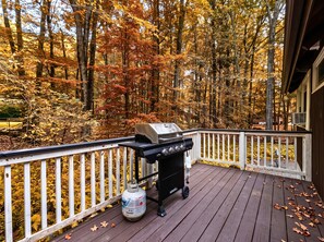 A barbecue grill on a wooden deck with a white railing, surrounded by autumn foliage. - Game Room, Hot Tub, Fire Pit, Near Ski Resorts (Tobyhanna Township)