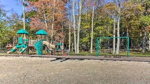 A playground with climbing structures and a swing set in a park with trees. - Firelight Escape w/ Hot Tub, Games & Resort Access (Tobyhanna Township)