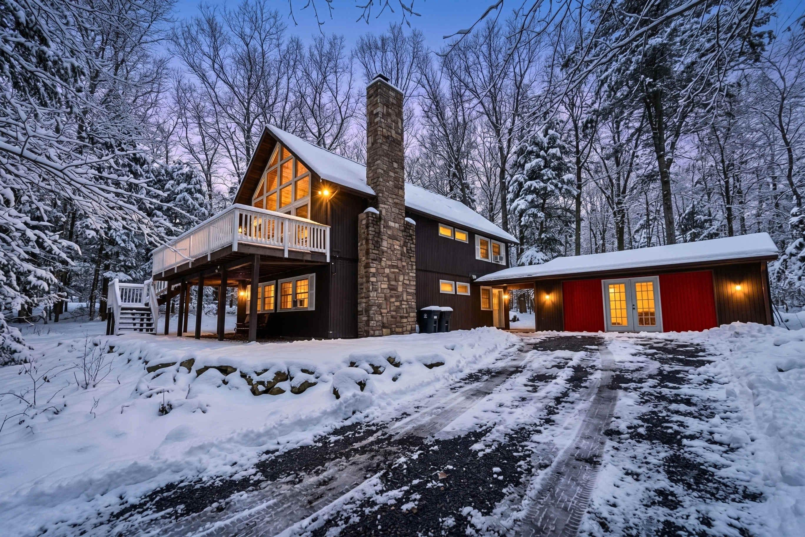 Une cabane à deux étages avec un balcon, une cheminée en pierre et une porte de garage rouge.
