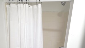A shower area with a white shower curtain and a showerhead. - Modern & Cozy Studio in Midtown (Atlanta)