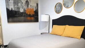 A bedroom with a bed, a cityscape painting, a floor lamp, and three round mirrors on the wall. - Modern & Cozy Studio in Midtown (Atlanta)