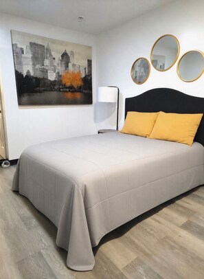 Ein Schlafzimmer mit einem Bett, einem Stadtbild, einer Stehlampe und drei runden Spiegeln an der Wand.