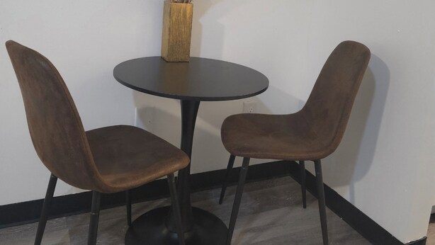 A round table with two chairs, a vase with dried plants, and a wall-mounted decorative piece. - Modern & Cozy Studio in Midtown (Atlanta)