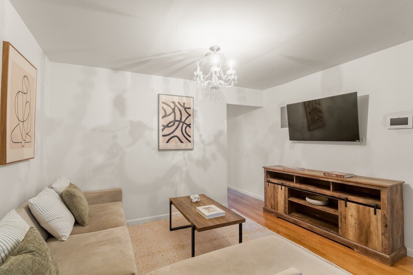 A living room with a sofa, coffee table, TV, and artwork on the walls.