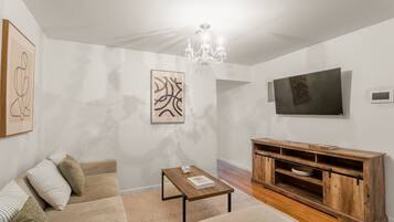 A living room with a sofa, coffee table, TV, and artwork on the walls.