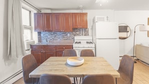 A compact kitchen with wooden cabinets, a microwave, a stove, and a dining table with chairs.