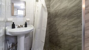A bathroom with a white sink, two soap dispensers, a mirror, and a shower with a white curtain.