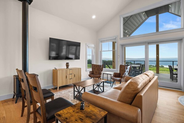 A spacious living room with a large TV, comfortable seating, and a view of the outdoors.