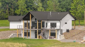 Een modern huis met twee verdiepingen, een balkon, een trap en een stenen fundering.