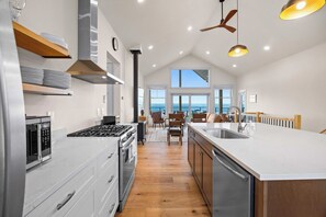 A modern kitchen with a central island, stainless steel appliances, and a view to the outside.